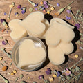 Heart-shaped lotion bar on a wooden surface with dried flowers