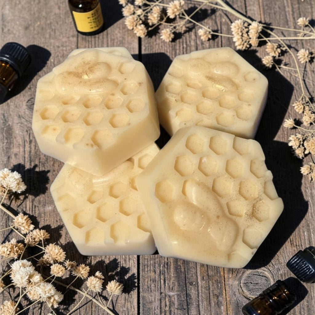 Hexagonal honeycomb-shaped beeswax lotion bars on a wooden surface with dried flowers and essential oil bottles.