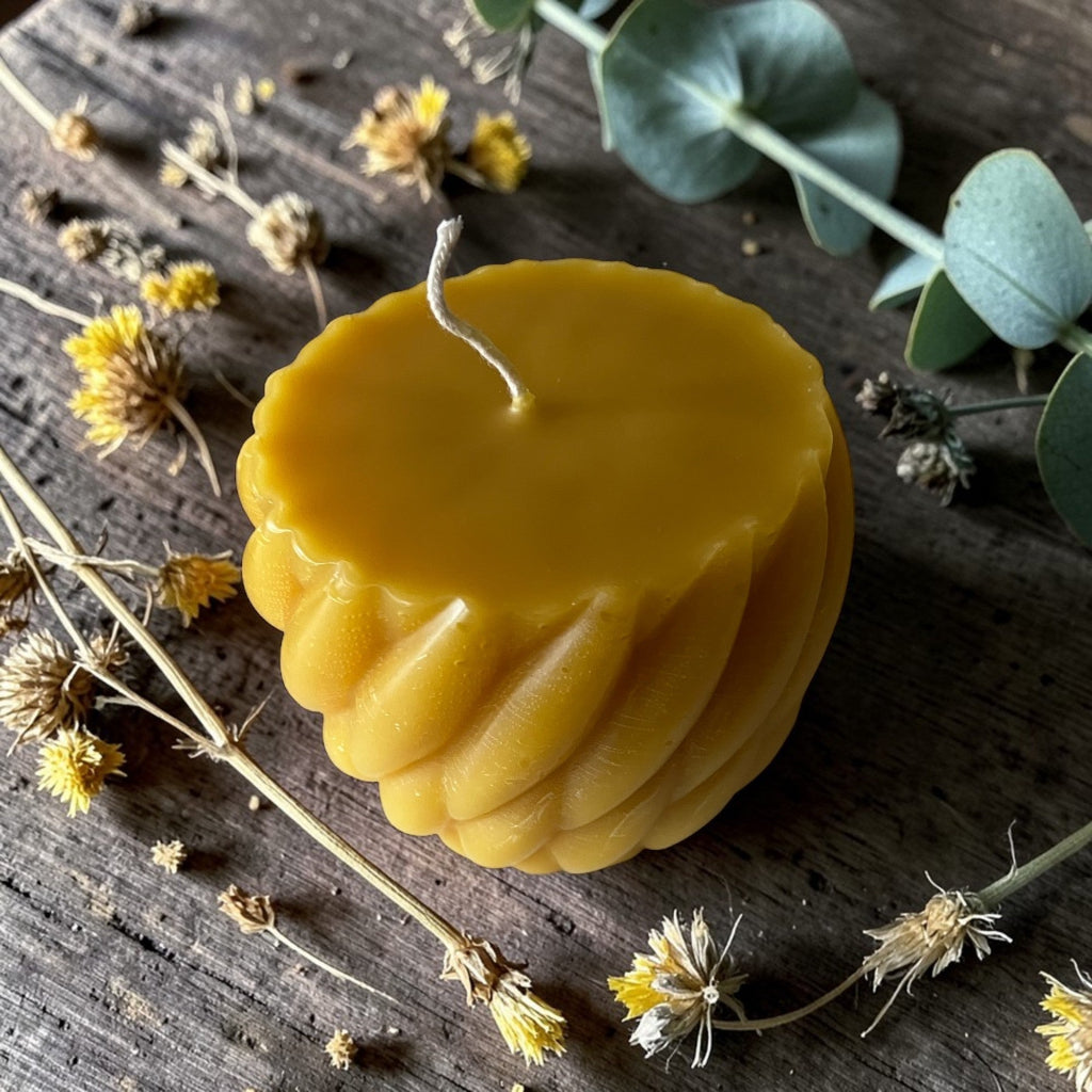 Beeswax candle on a wooden surface with dried flowers and leaves
