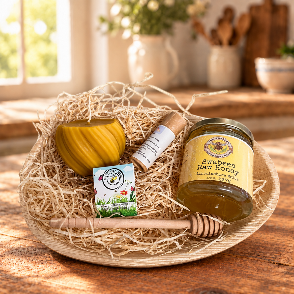 Honey, candle and balm gift set arranged in an oval tray on a rustic kitchen table