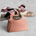 Swabees wildflower raw honey gift set in a blush-pink faux leather bag with a wooden dipper and patterned ribbon.